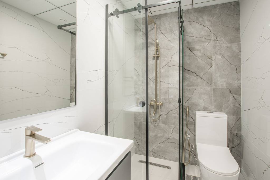 Bright modern bathroom with a glass shower screen and marble-effect tiles